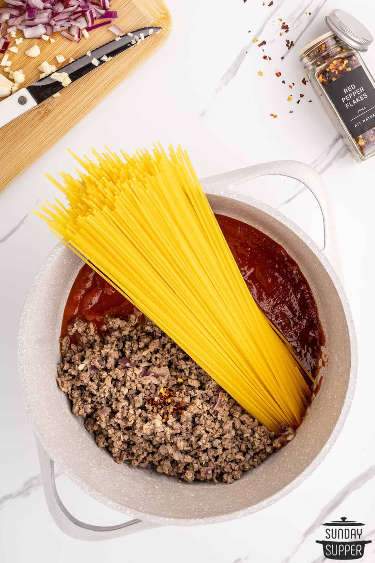 the meat and sauce in a pot with the noodles added