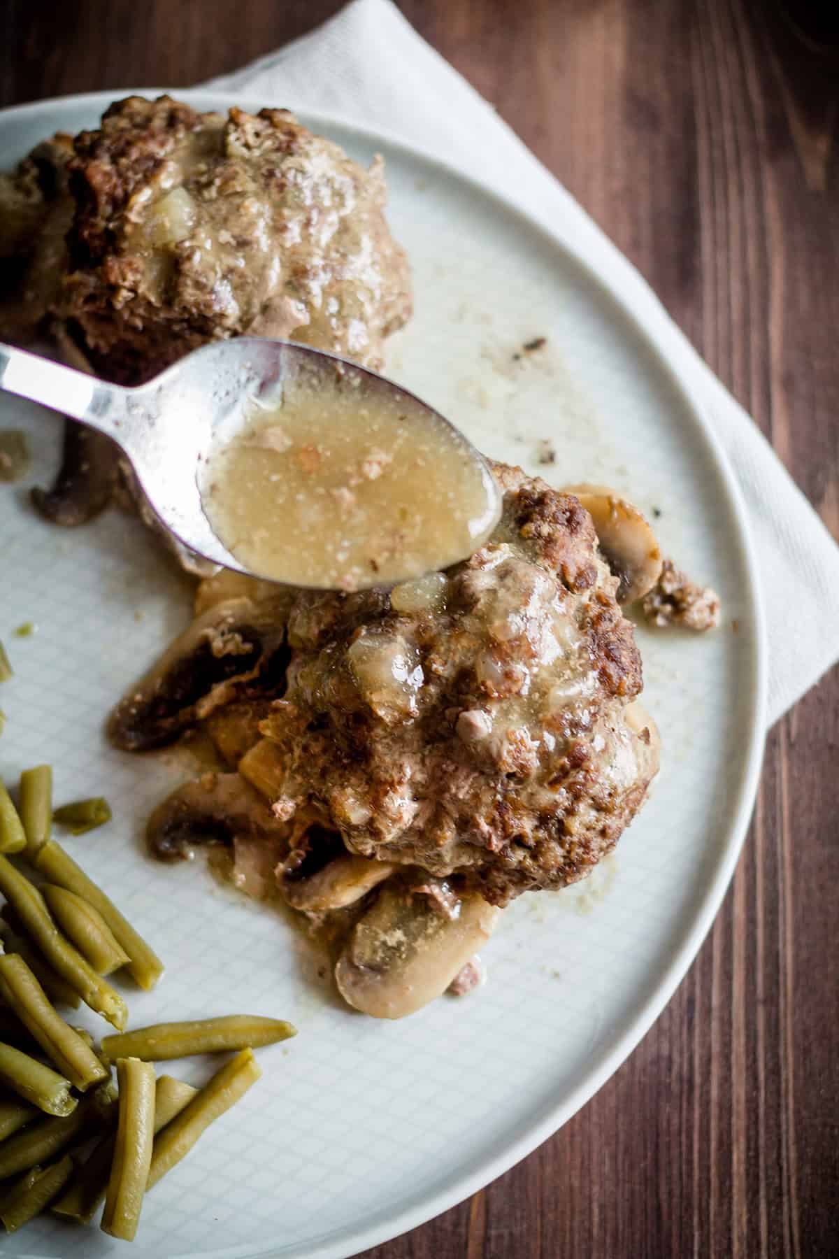 gravy being poured over two salisbury steaks