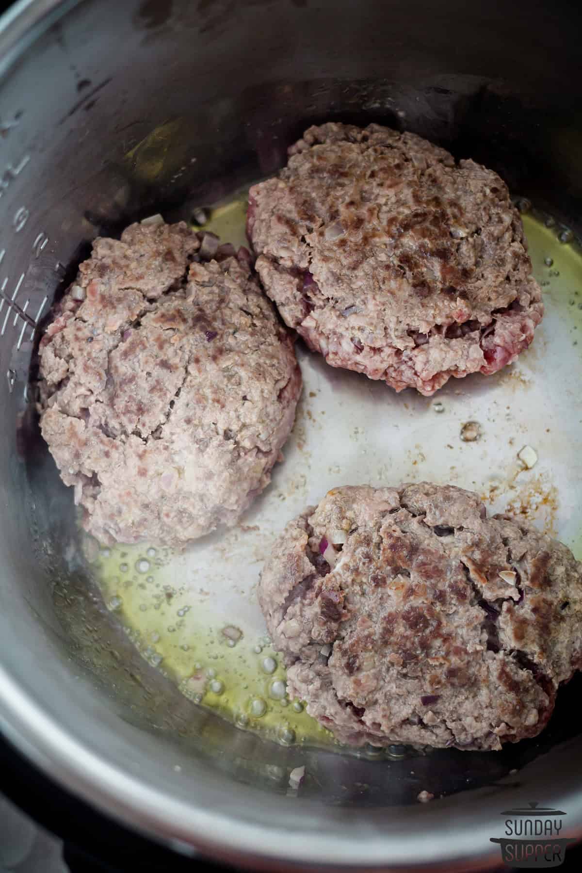 the steaks being browned in the pot