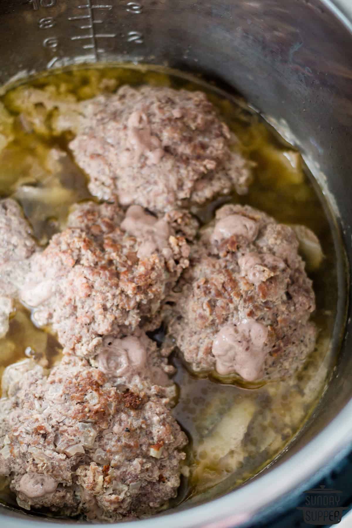 five salisbury steaks in the pot with broth