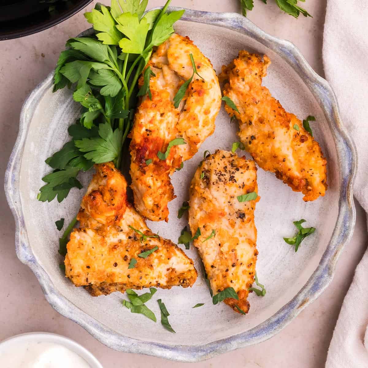 air fryer chicken strips on a plate with fresh herbs