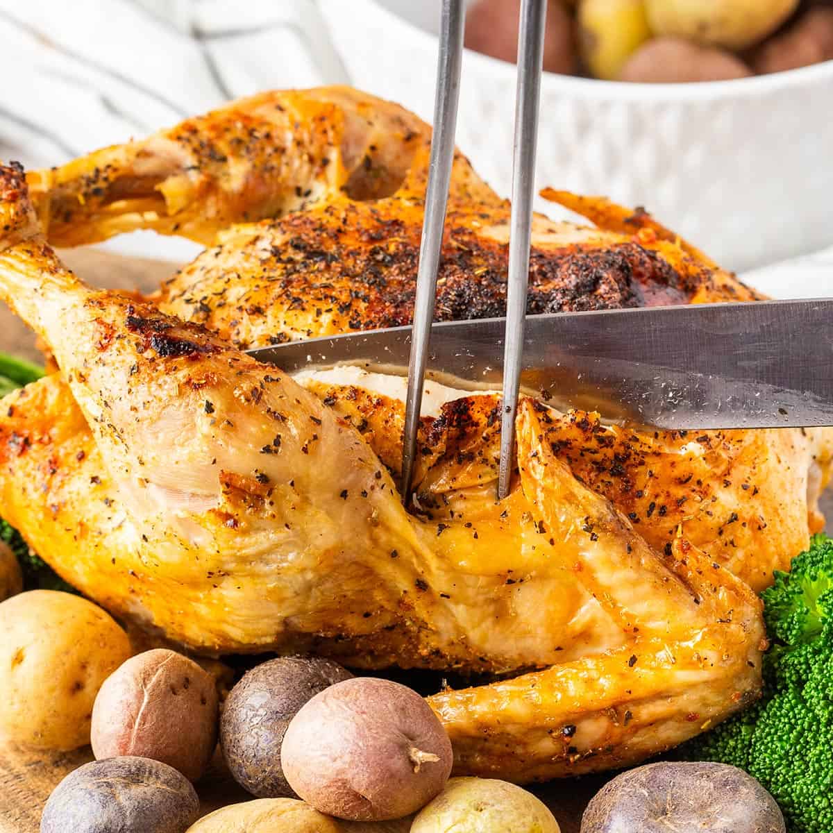 using a knife and meat tongs to slice air fryer chicken