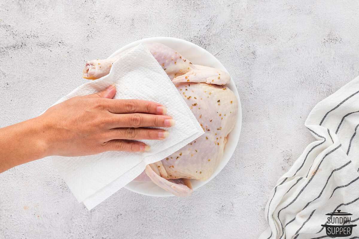 the chicken being pat dry with paper towels