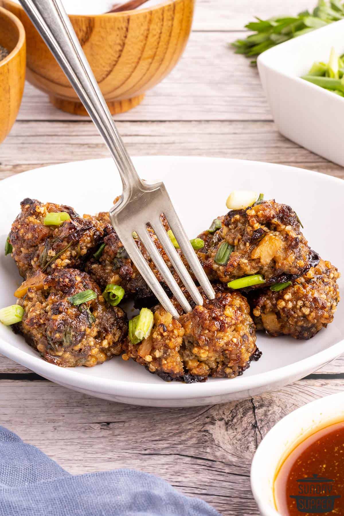 a fork picking up a meatball off a plate