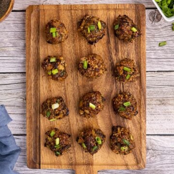 a cutting board filled with lined up asian meatballs
