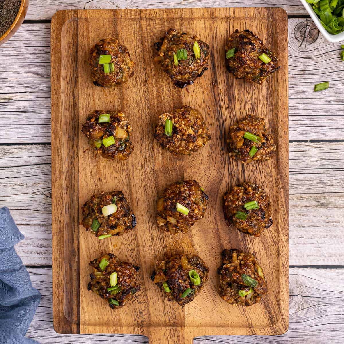 a cutting board filled with lined up asian meatballs