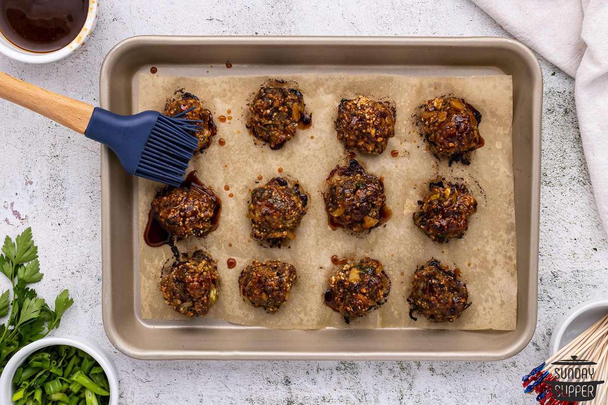 extra hoisin being brushed over cooked meatballs