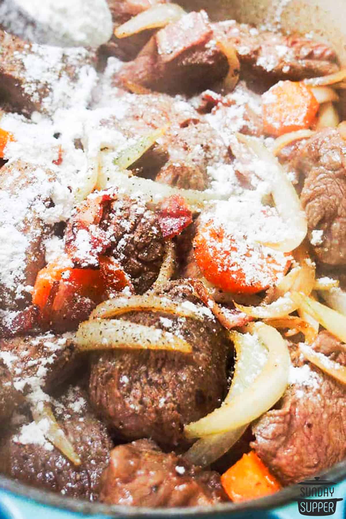 sprinkling flour over bourguignon ingredients