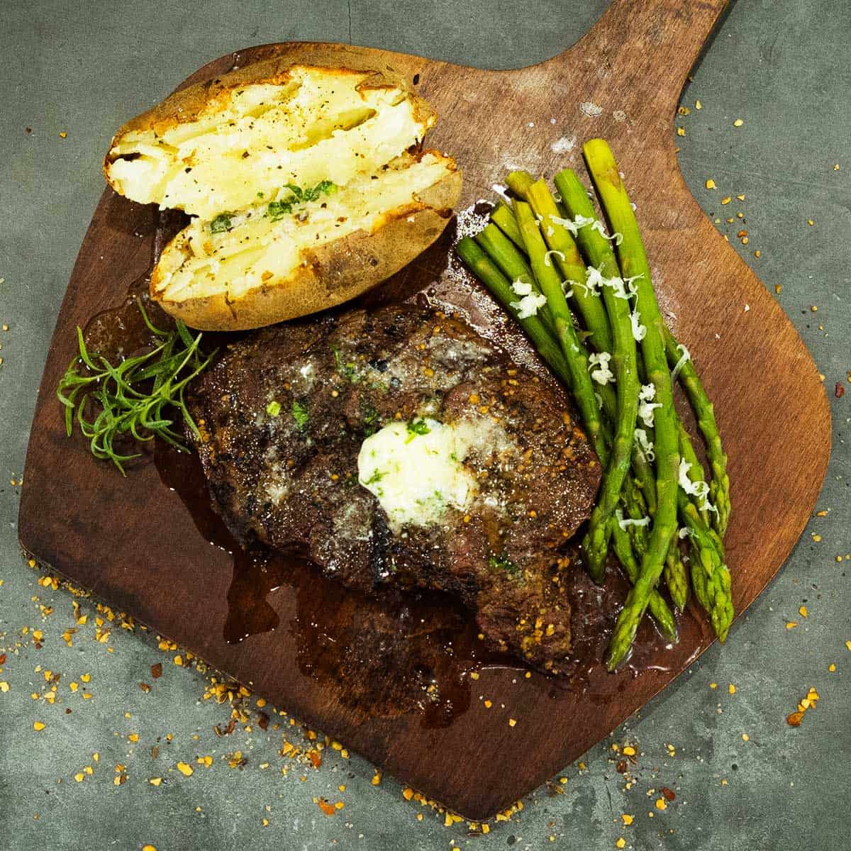 a grilled ribeye steak with asparagus and a potato