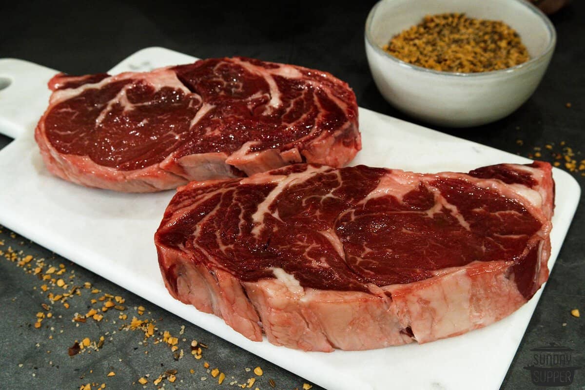 two steaks on a cutting board before being cooked