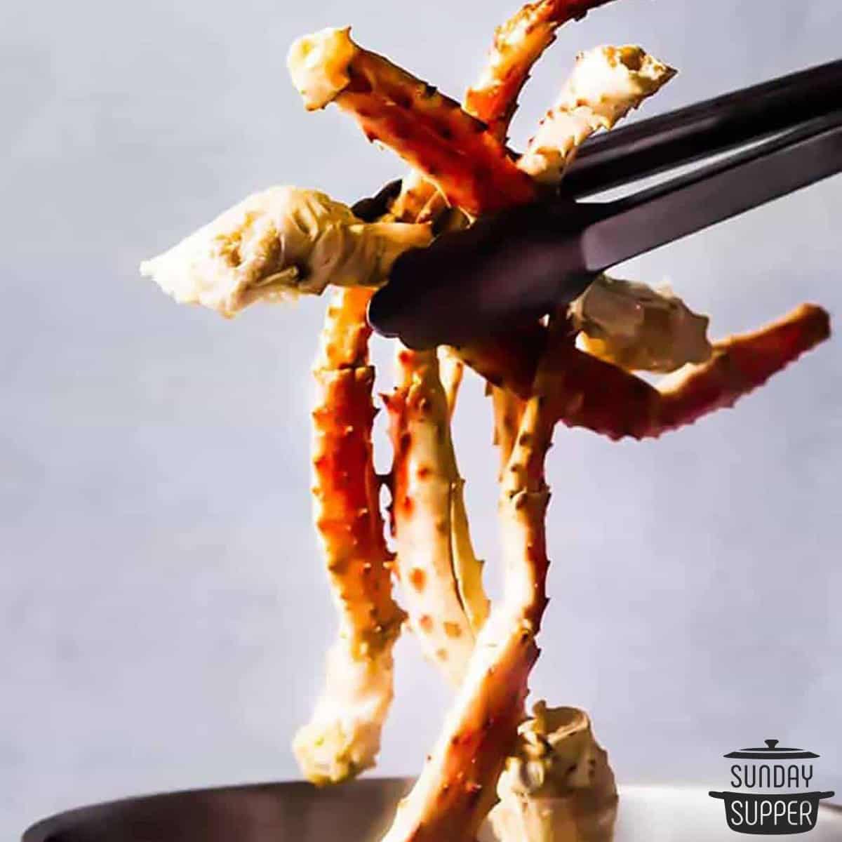 crab legs being held up with tongs