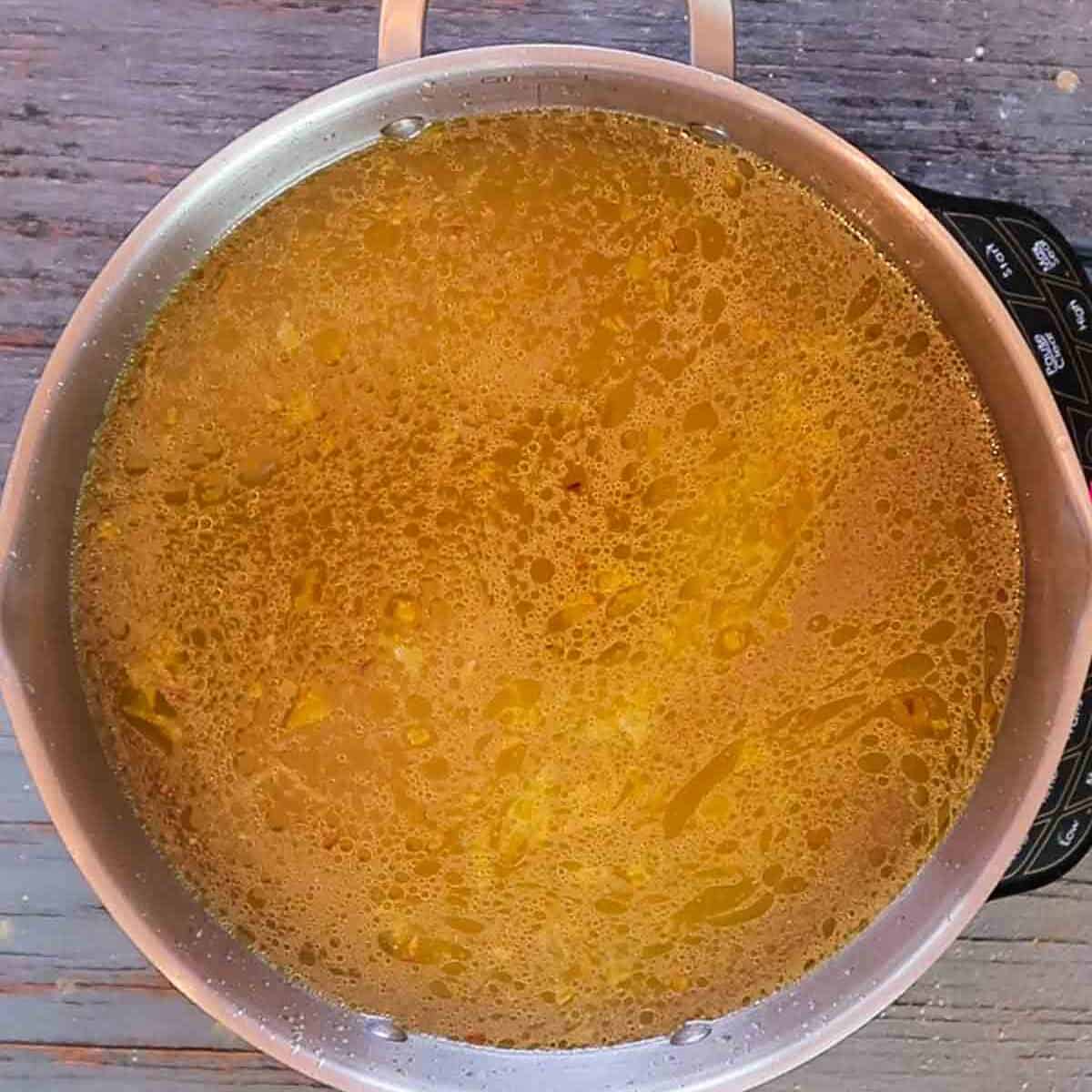 Italian wedding soup with chicken broth added in pot