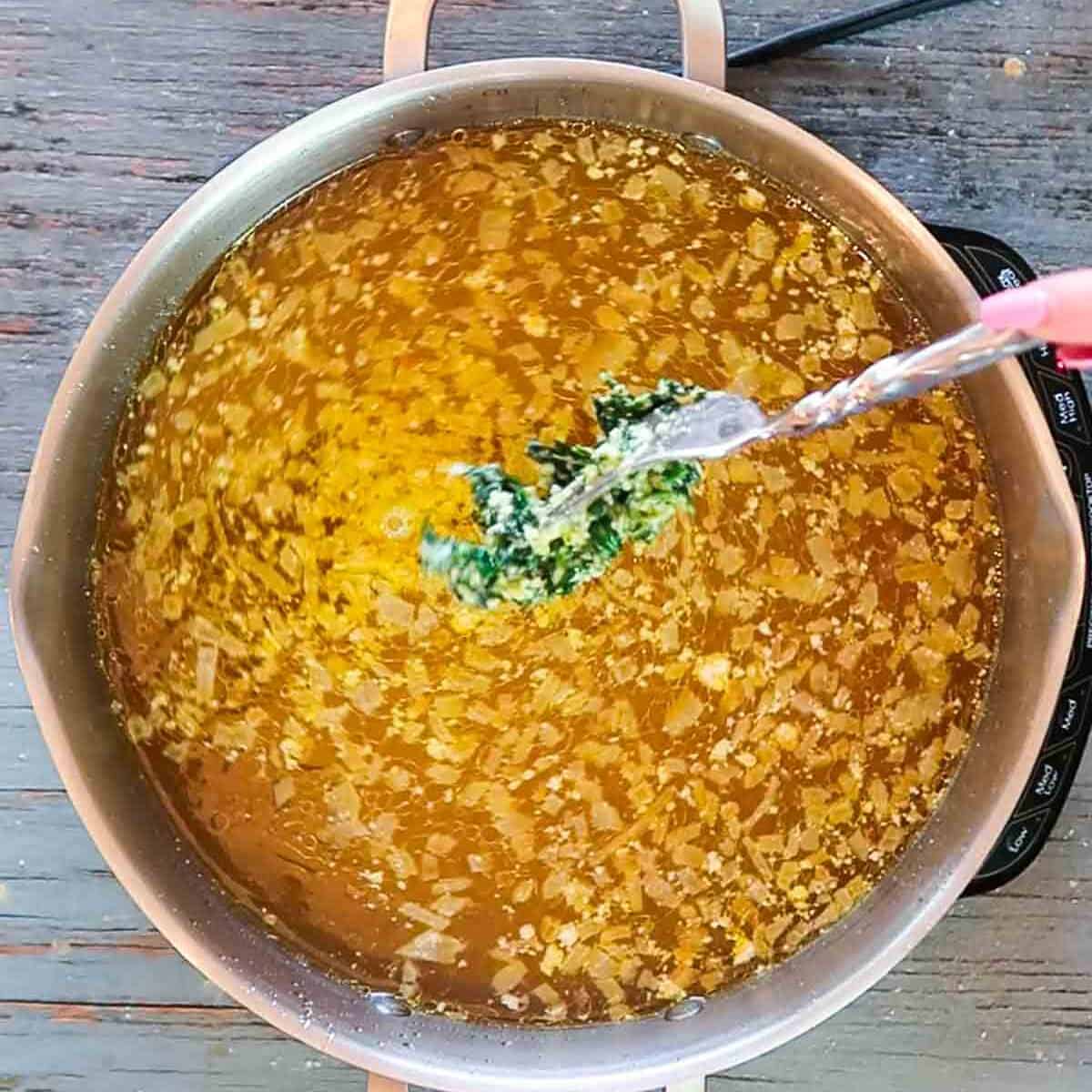 Adding forkfuls of spinach egg mixture to Italian wedding soup