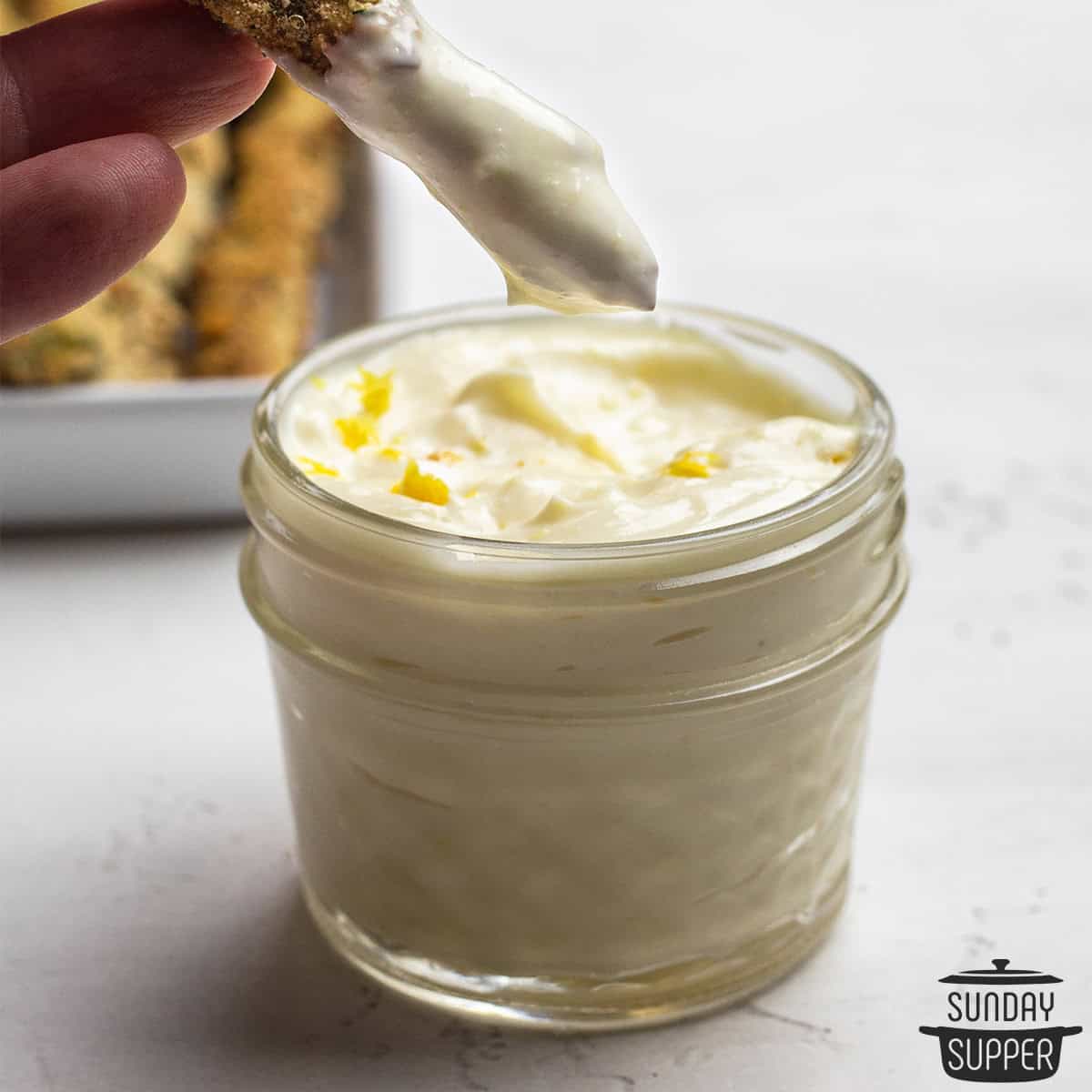 a spear of asparagus being dipped in aioli