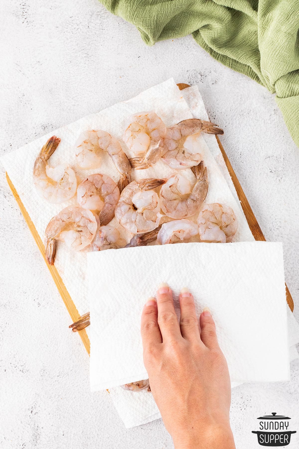 the shrimp being pat dry after peeling and cleaning