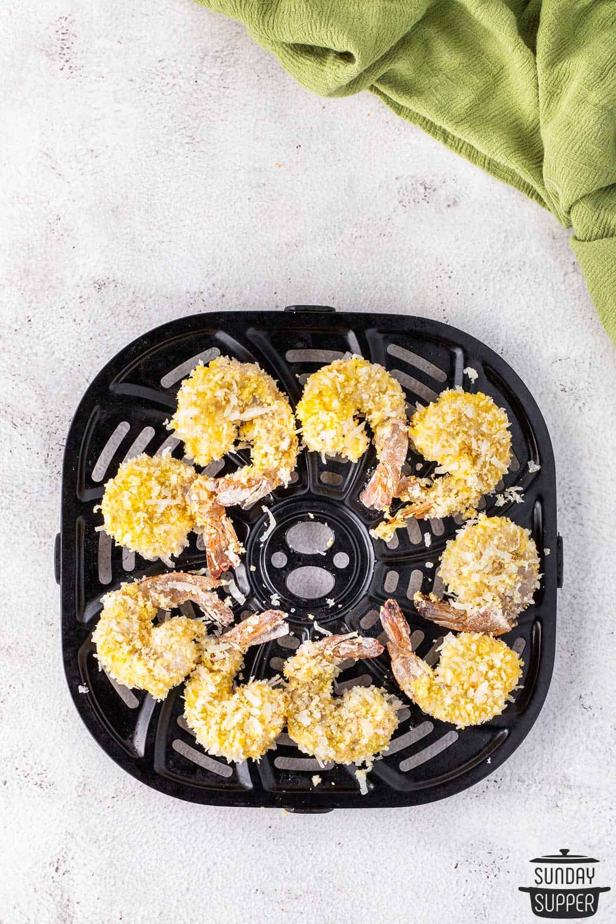 breaded shrimp placed in the air fryer basket