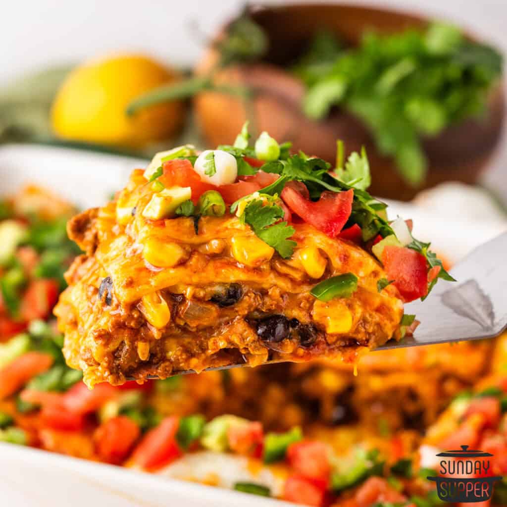 a spatula holding up a neat slice of enchilada casserole