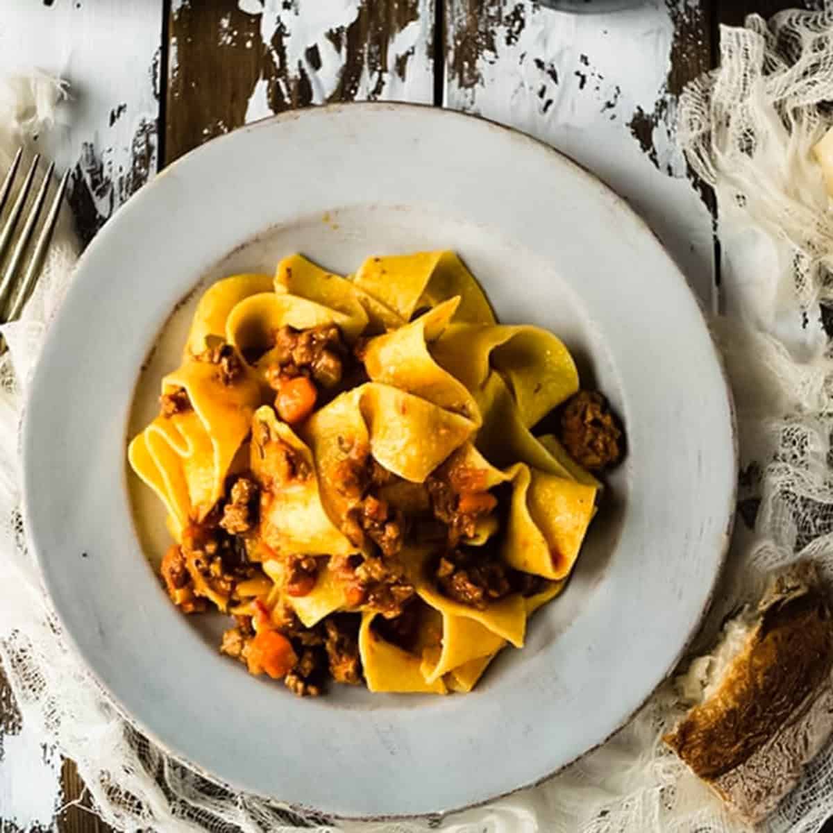 a white dinner plate with bolognese sauce and pasta