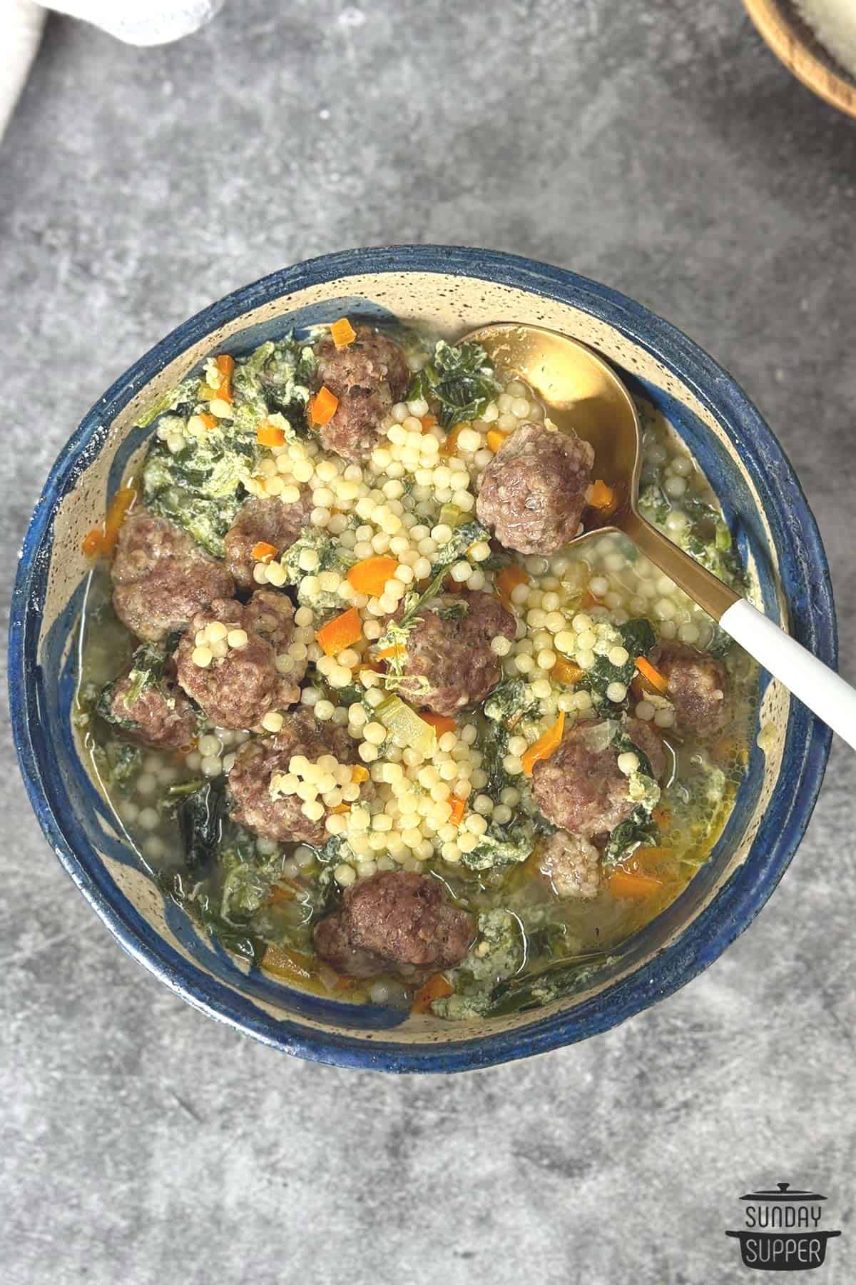 A bowl of wedding soup with a spoon