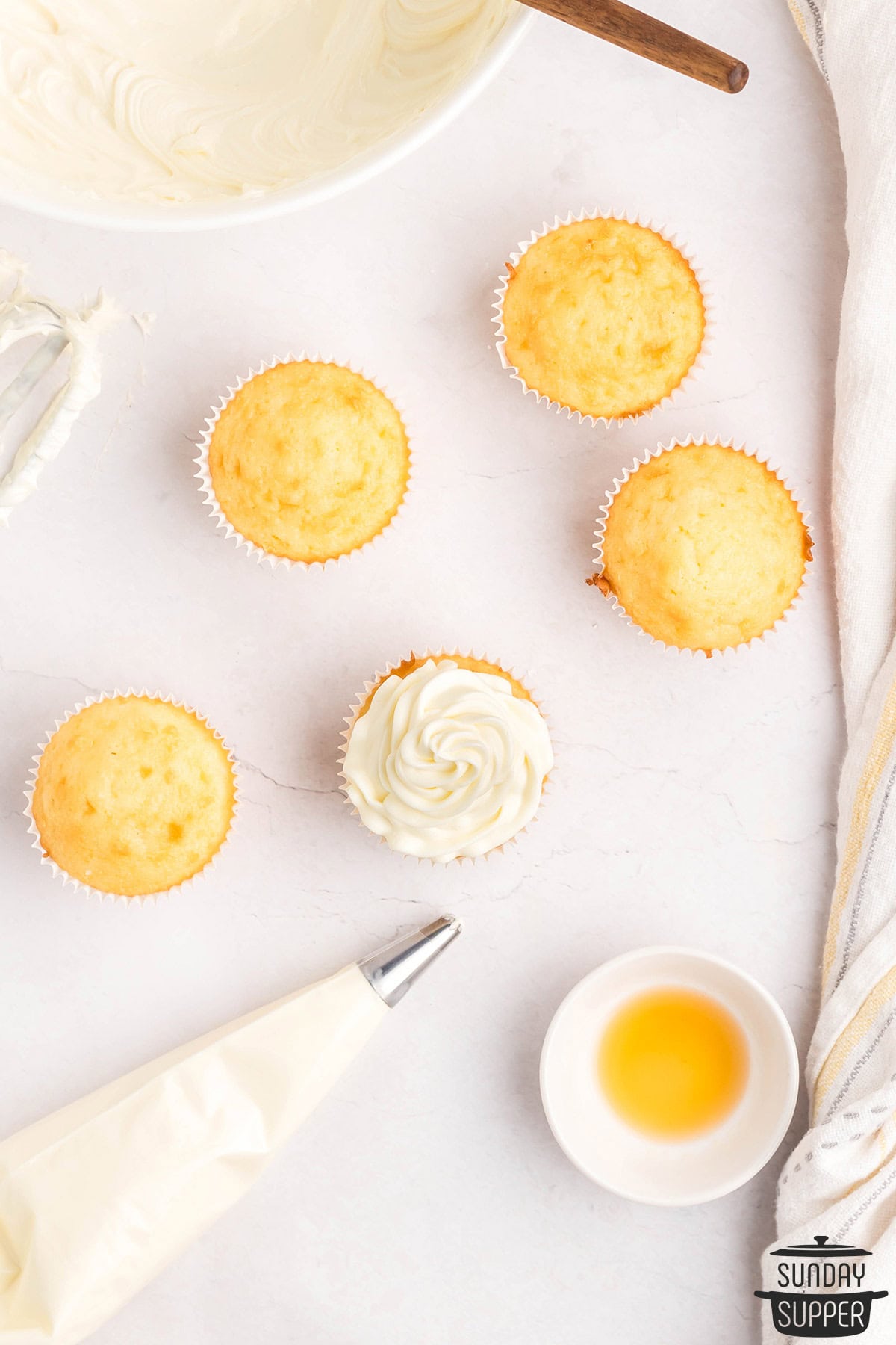 frosting being piped on to cupcakes