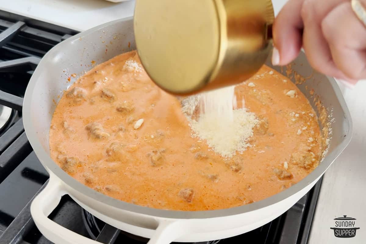 adding parmesan to sauce