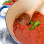 a wooden spoon in a pot of sugo tomato sauce