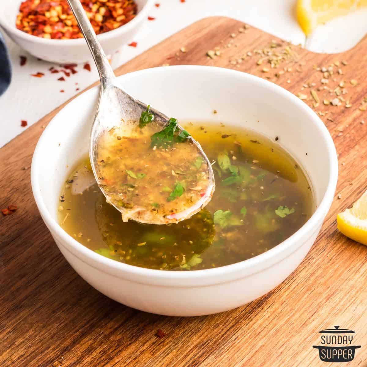 a spoonful of italian dressing over a bowl