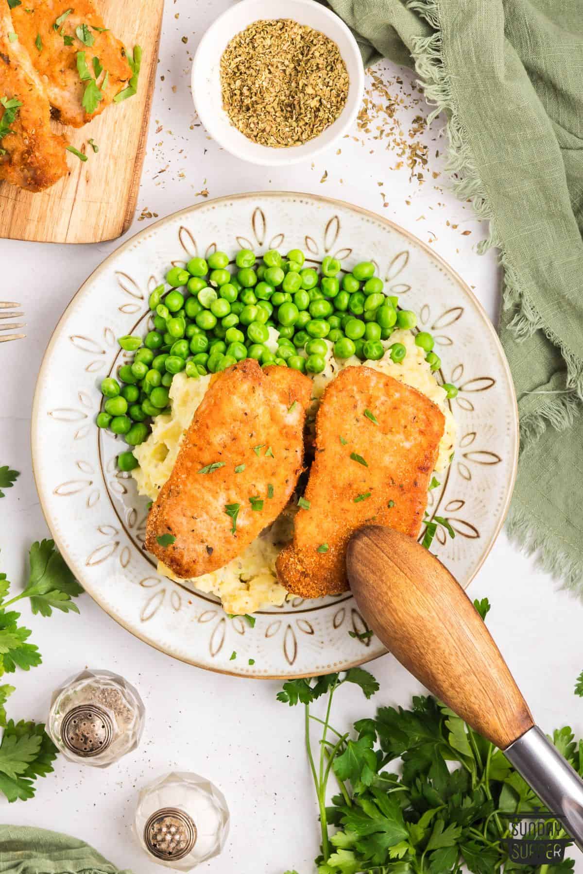 a plate of shake and bake pork chops with peas and mashed potatoes