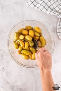 stirring around potatoes in a bowl with oil