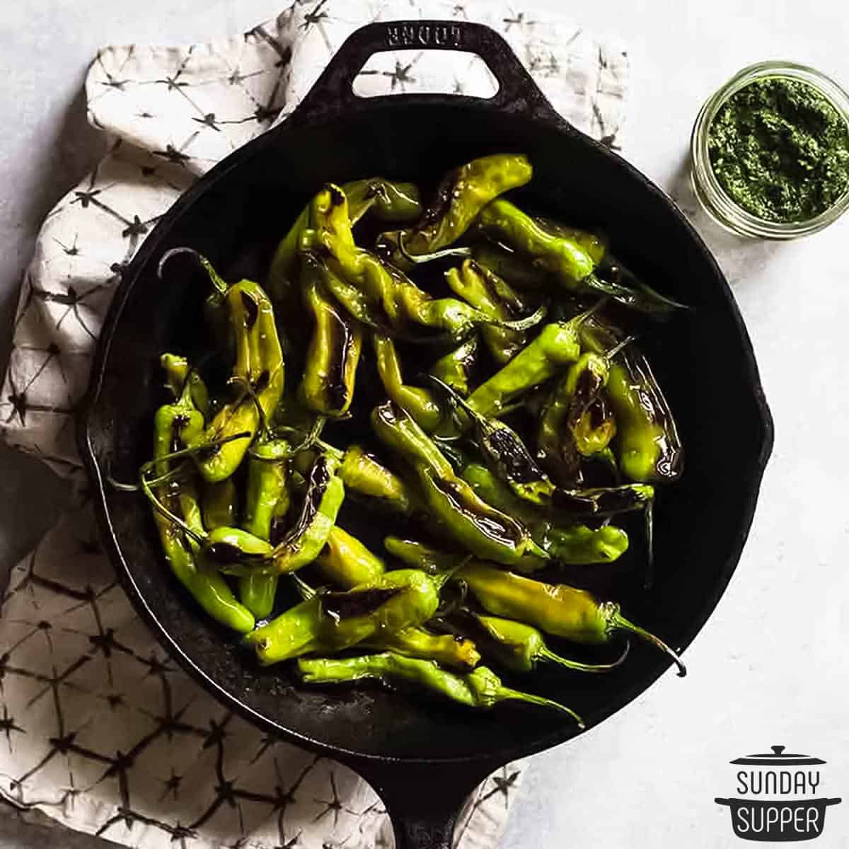 a cast iron pan filled with blistered peppers