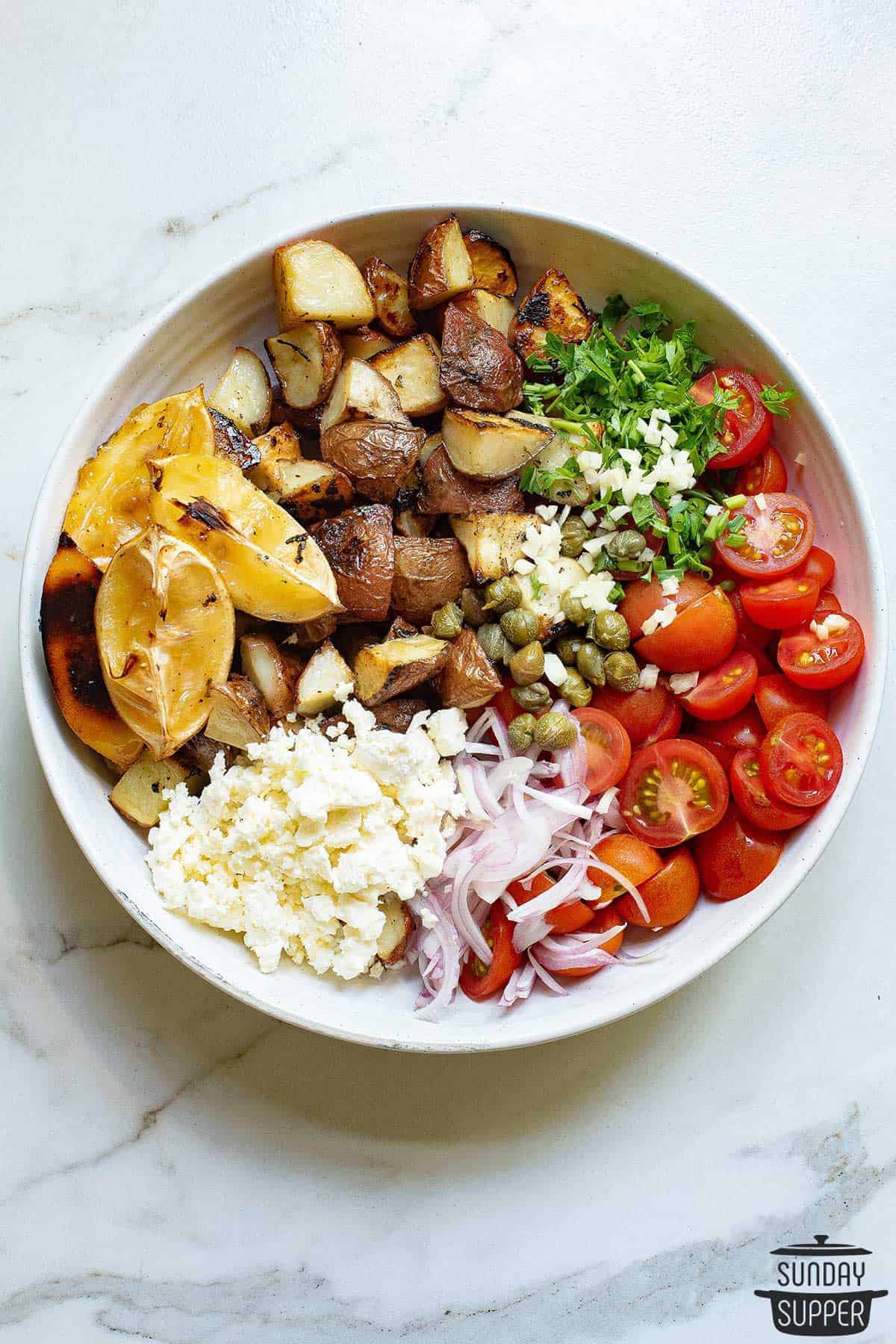 a bowl of combined lemon potato salad ingredients before being mixed