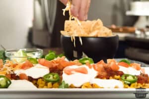 cheese being sprinkled over mexican layer dip