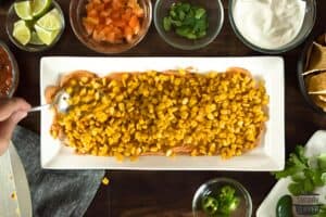 corn being added to the top of the cream cheese mixture