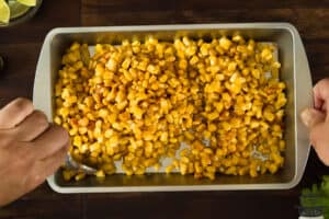 the corn in a roasting tin being tossed in spices