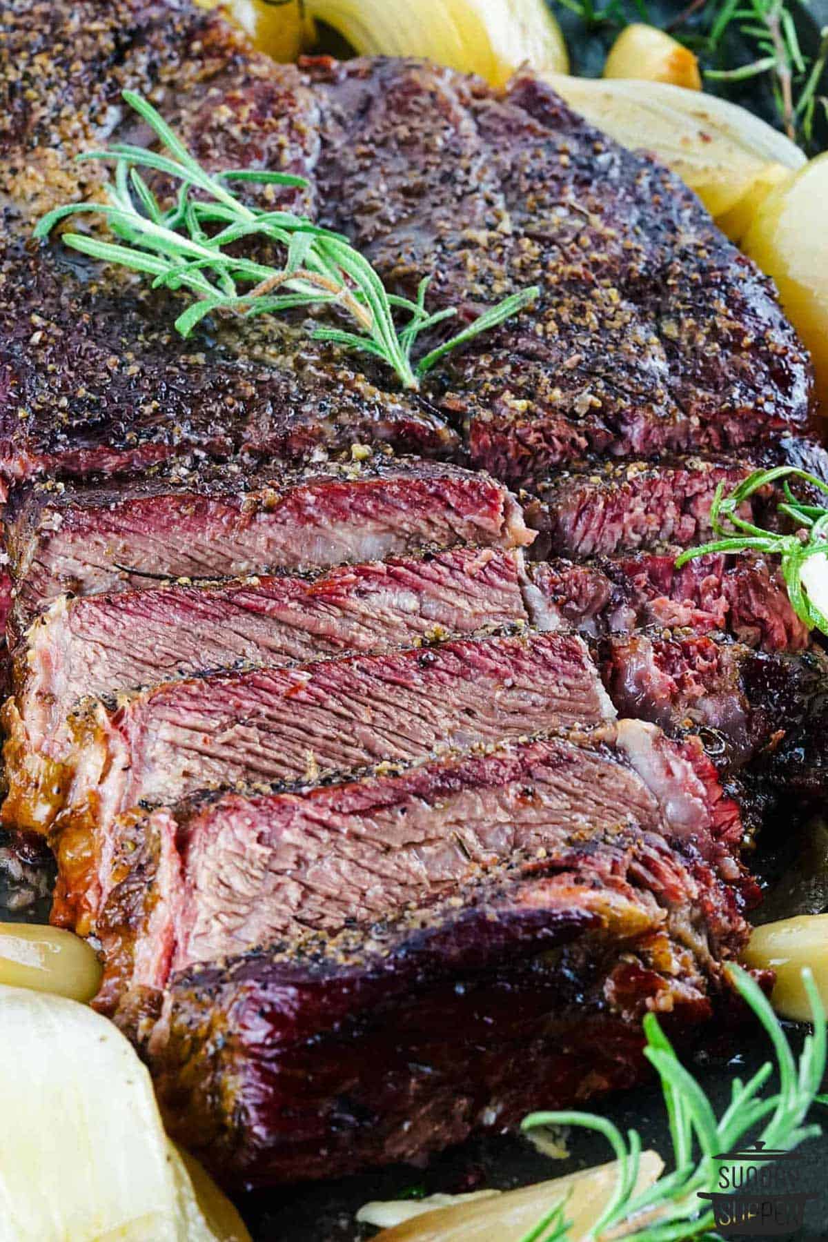 a beef chuck roast with herbs and onions halfway sliced