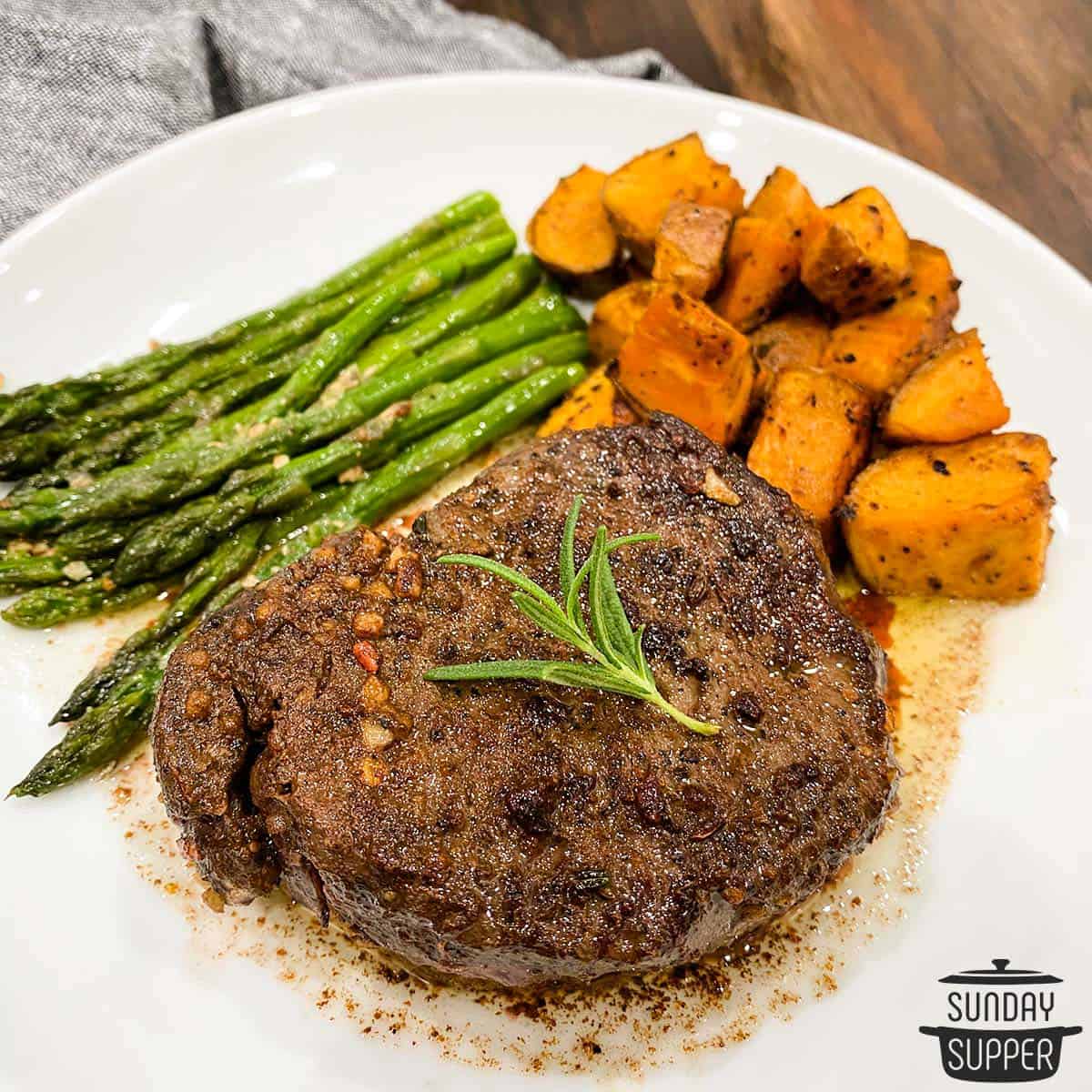 sous vide filet mignon on a dinner plate with asparagus and sweet potatoes