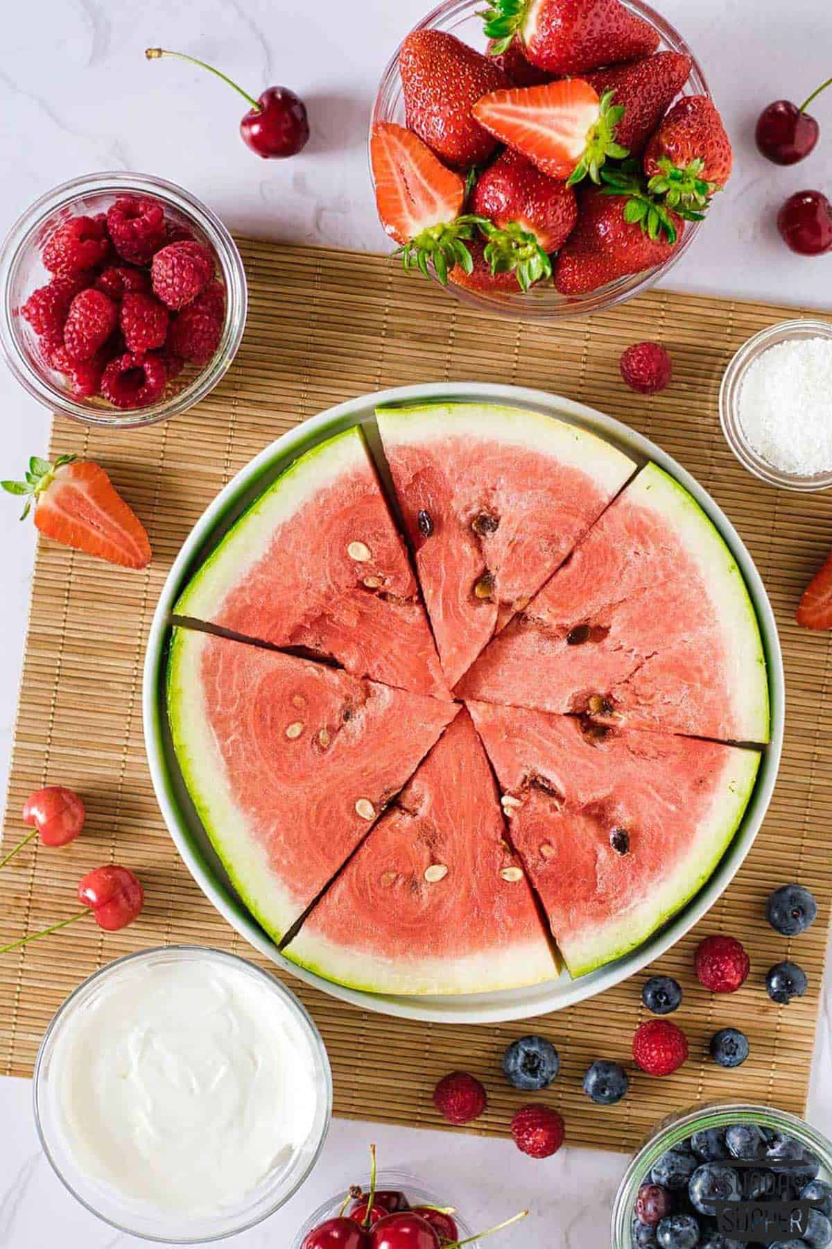 a sliced watermelon round with berries and yogurt ready